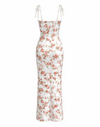 A white satin slip dress with a pink and green floral print, featuring thin adjustable tie-shoulder straps, shown against a plain white background.