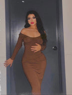 Woman in a brown dress against a dark background