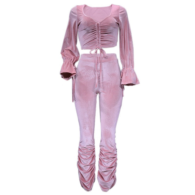 Pink velvet outfit with long sleeves and ruched design on a white background