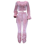 Pink velvet outfit with long sleeves and ruched design on a white background