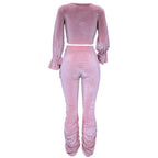 Pink velvet outfit with long sleeves and ruched pants on a white background