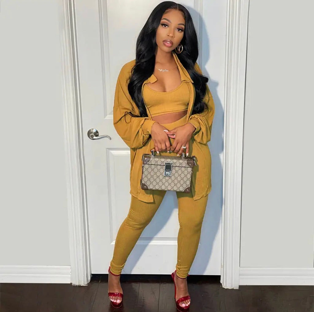Woman in mustard yellow outfit holding a Gucci handbag against a white door.
