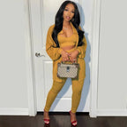 Woman in mustard yellow outfit holding a Gucci handbag against a white door.