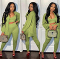 Woman in a green outfit holding a handbag against a white door background