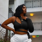 Woman in black one sleeve crop top and white sweat pants standing in front of a building.